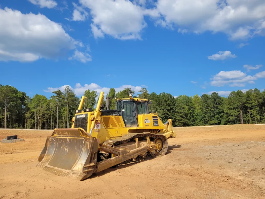 青空の下で工事現場に置かれているブルドーザーの画像