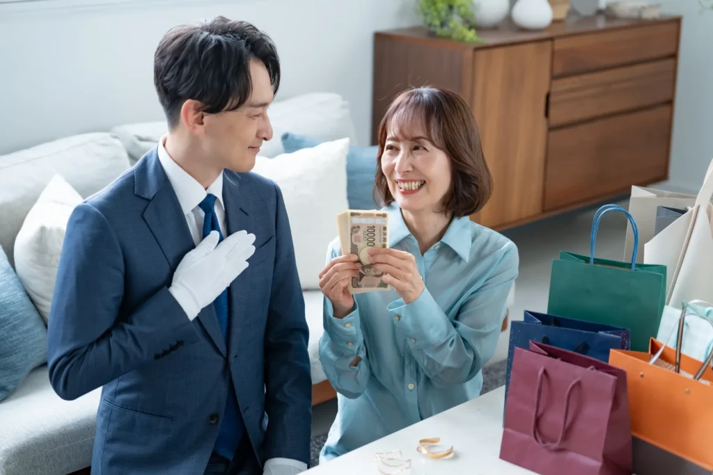 出張買取で現金を手にする女性と査定員の画像